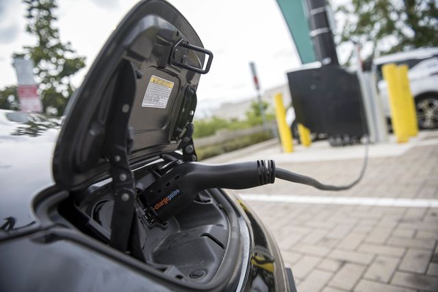 A small panel door is lifted as an electric charger is plugged into an electric vehicle at a charging station in Brooklyn in September 2017. Charging stations can become more ubiquitous across New York by 2030 if the state Department of Environmental Conservation succeeds in implementing new policies that can improve the environment.